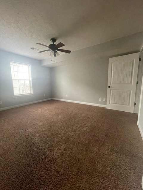 an empty room with a ceiling fan and a white door