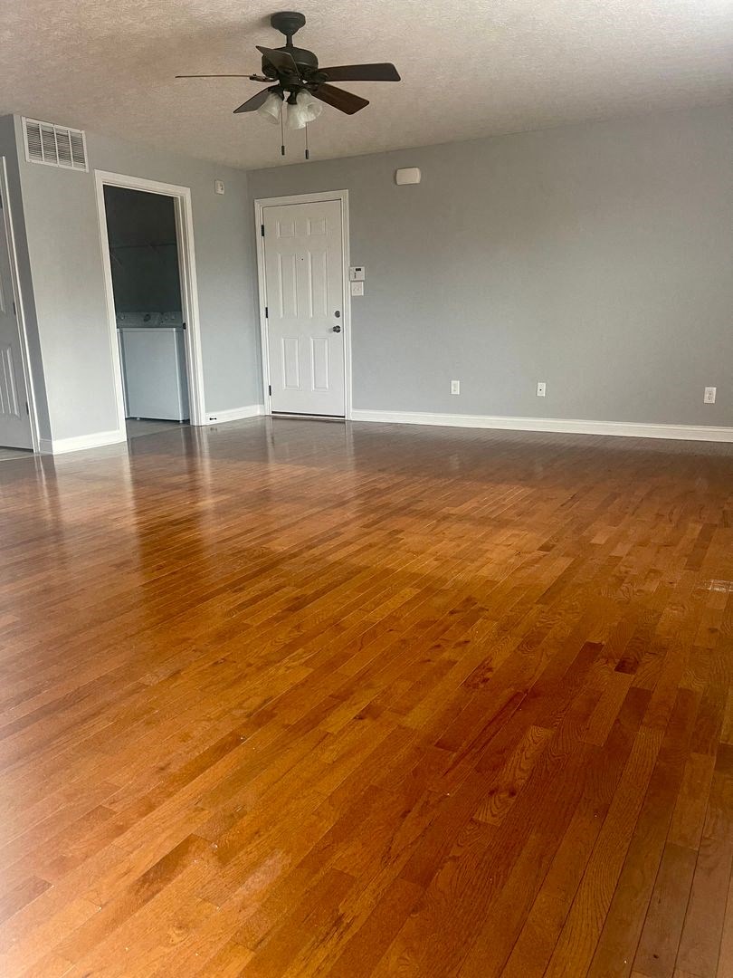 an empty living room with wooden floors and a ceiling fan