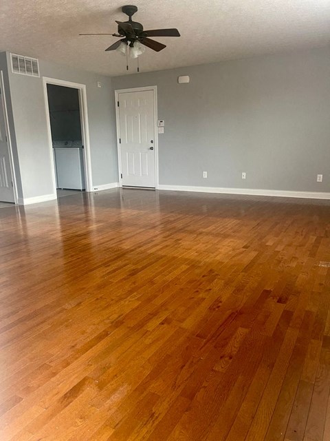 an empty living room with wooden floors and a ceiling fan