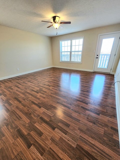 an empty living room with hard wood floors and a ceiling fan