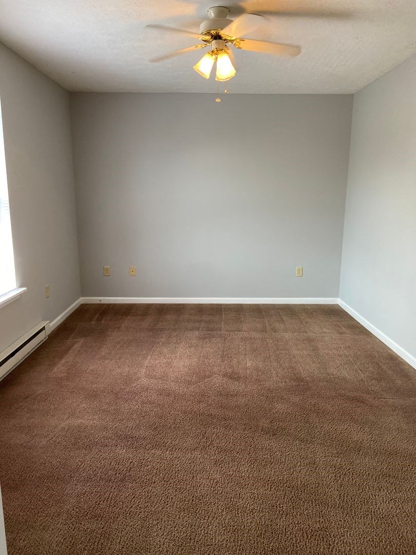 a empty room with a ceiling fan and a carpet