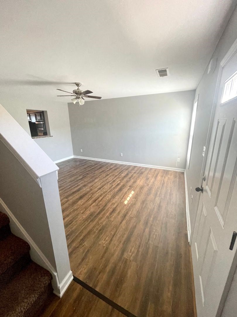 a empty living room with wood floors and a ceiling fan
