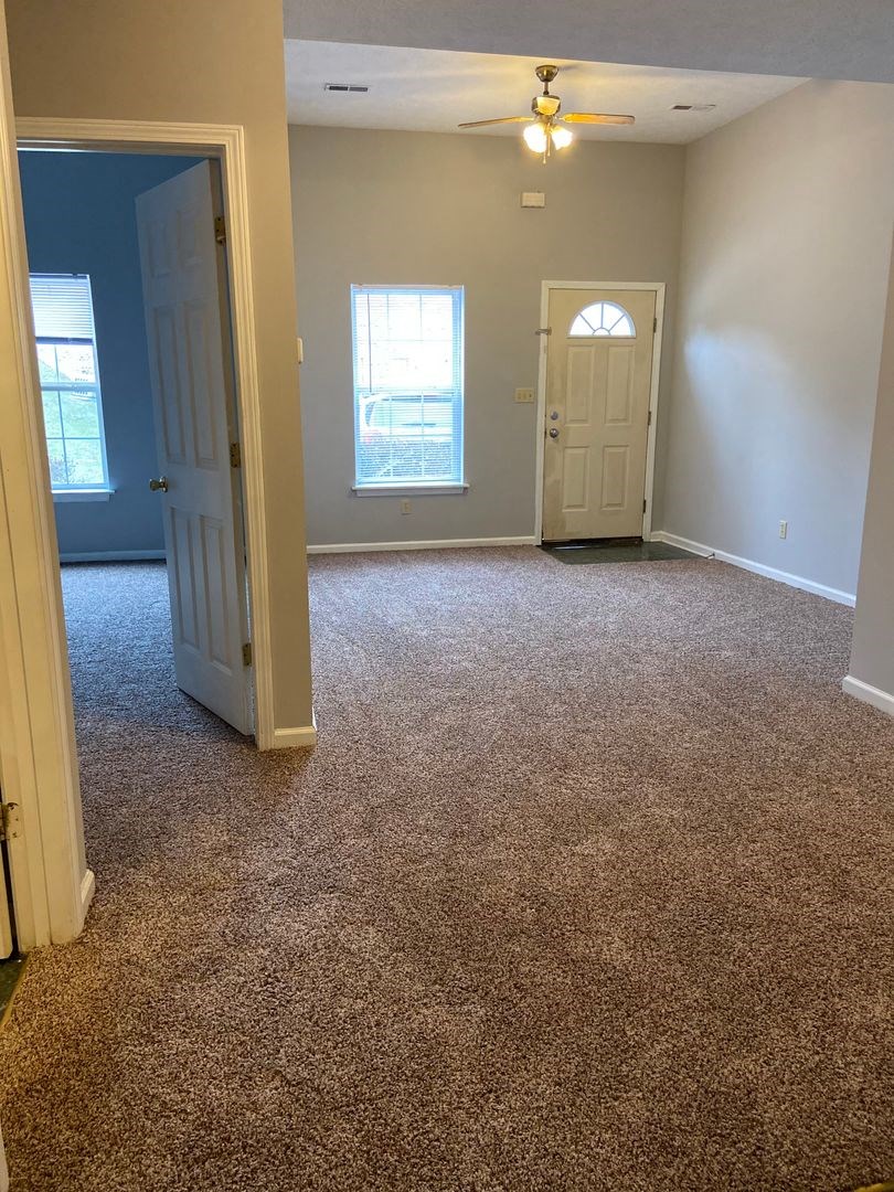 an empty living room with a carpeted floor and a door
