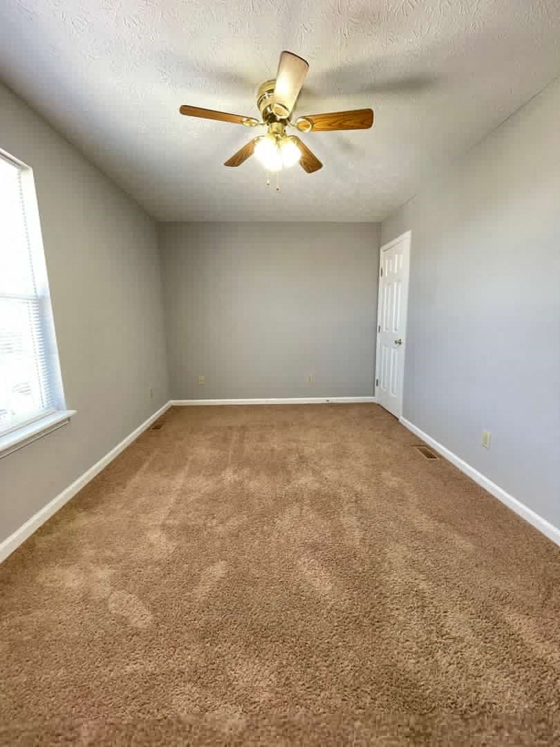 an empty room with a ceiling fan and a window