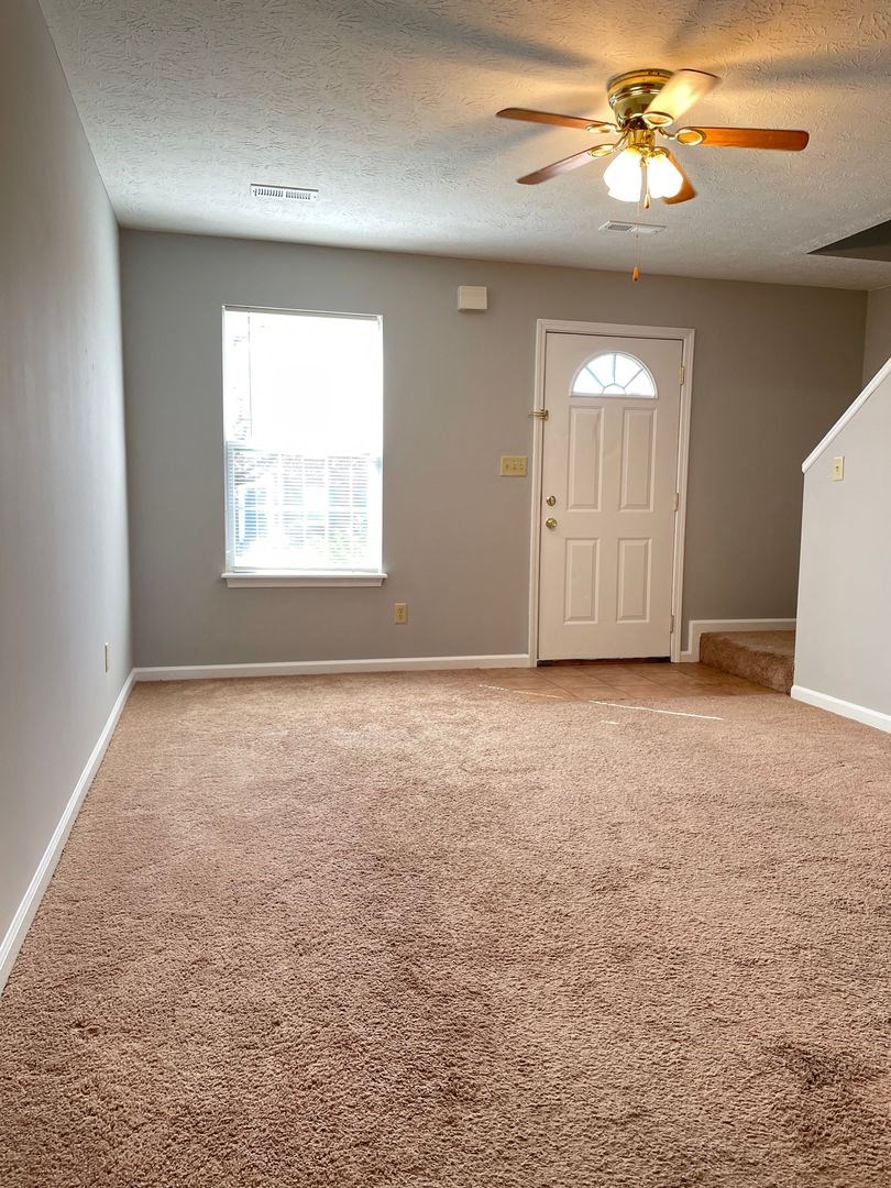 an empty room with a ceiling fan and a door
