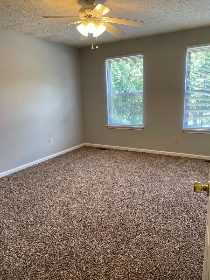 an empty room with carpet and a ceiling fan