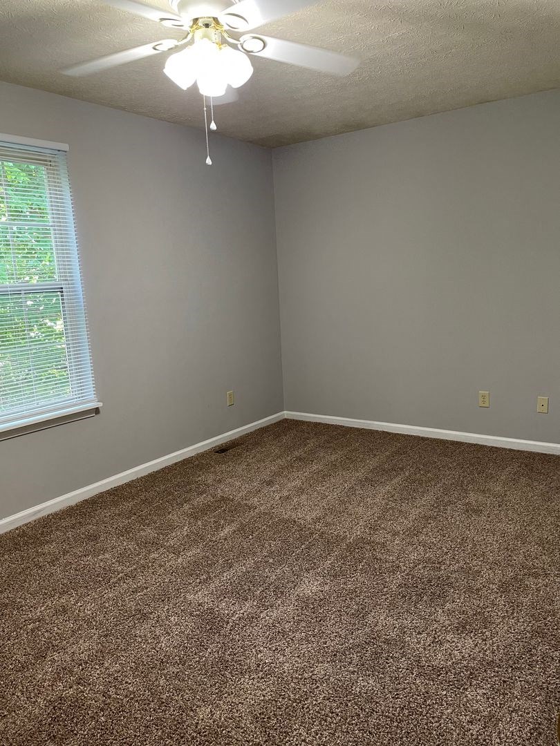 an empty room with carpet and a ceiling fan