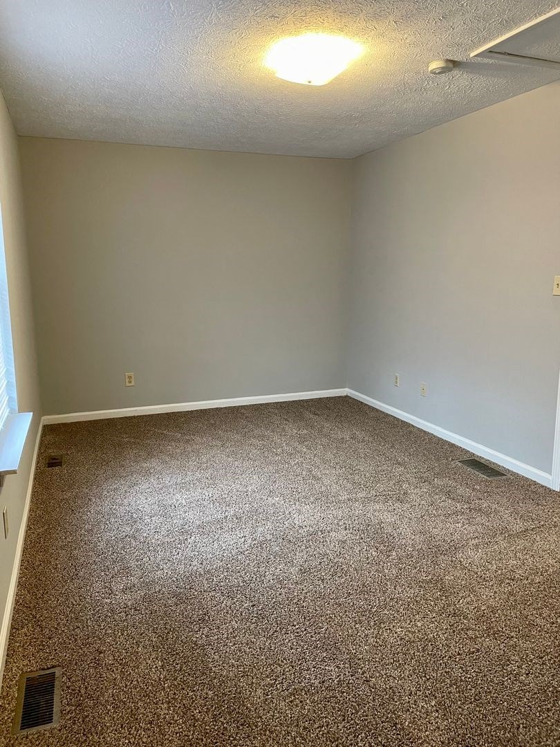 an empty room with a carpeted floor and a window