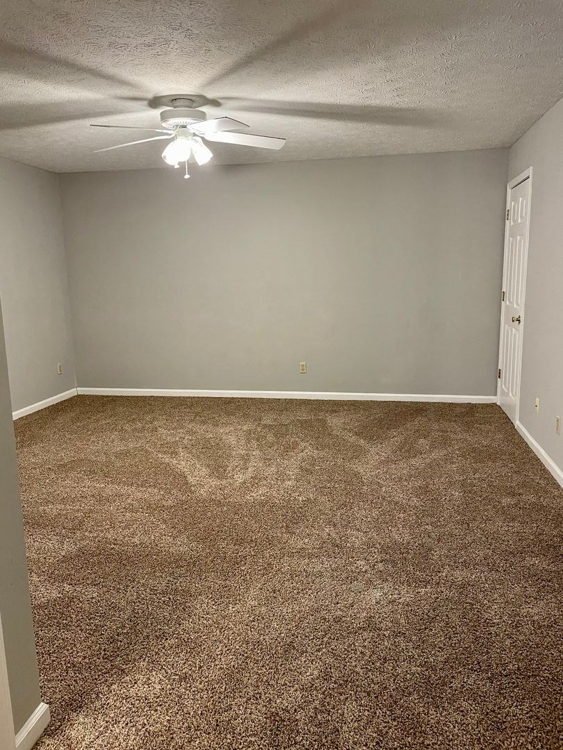 an empty room with carpet and a ceiling fan