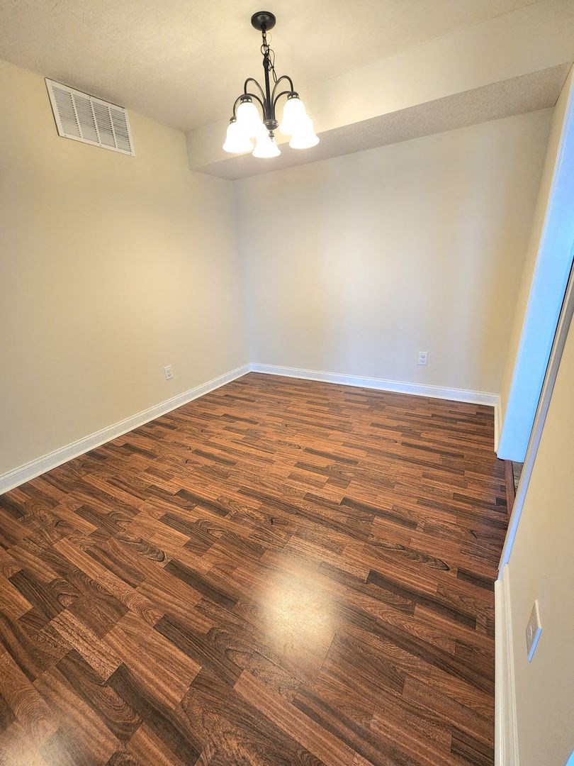 an empty living room with wood flooring and a chandelier