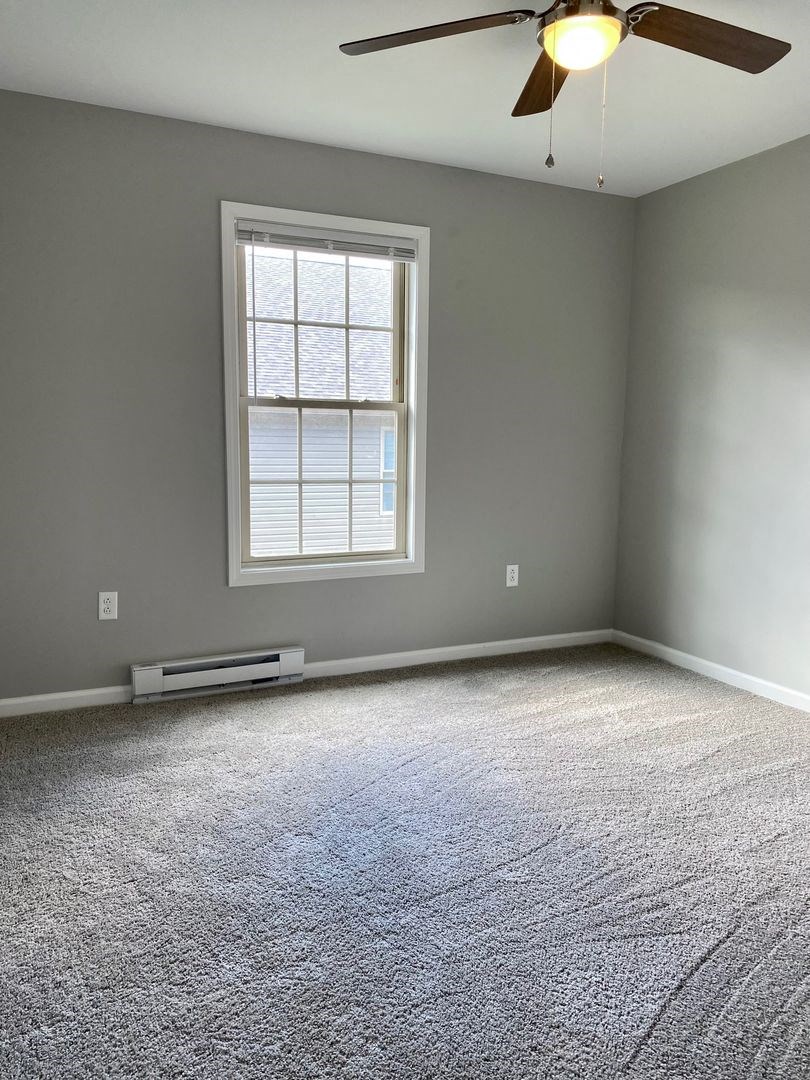 an empty room with a ceiling fan and a window