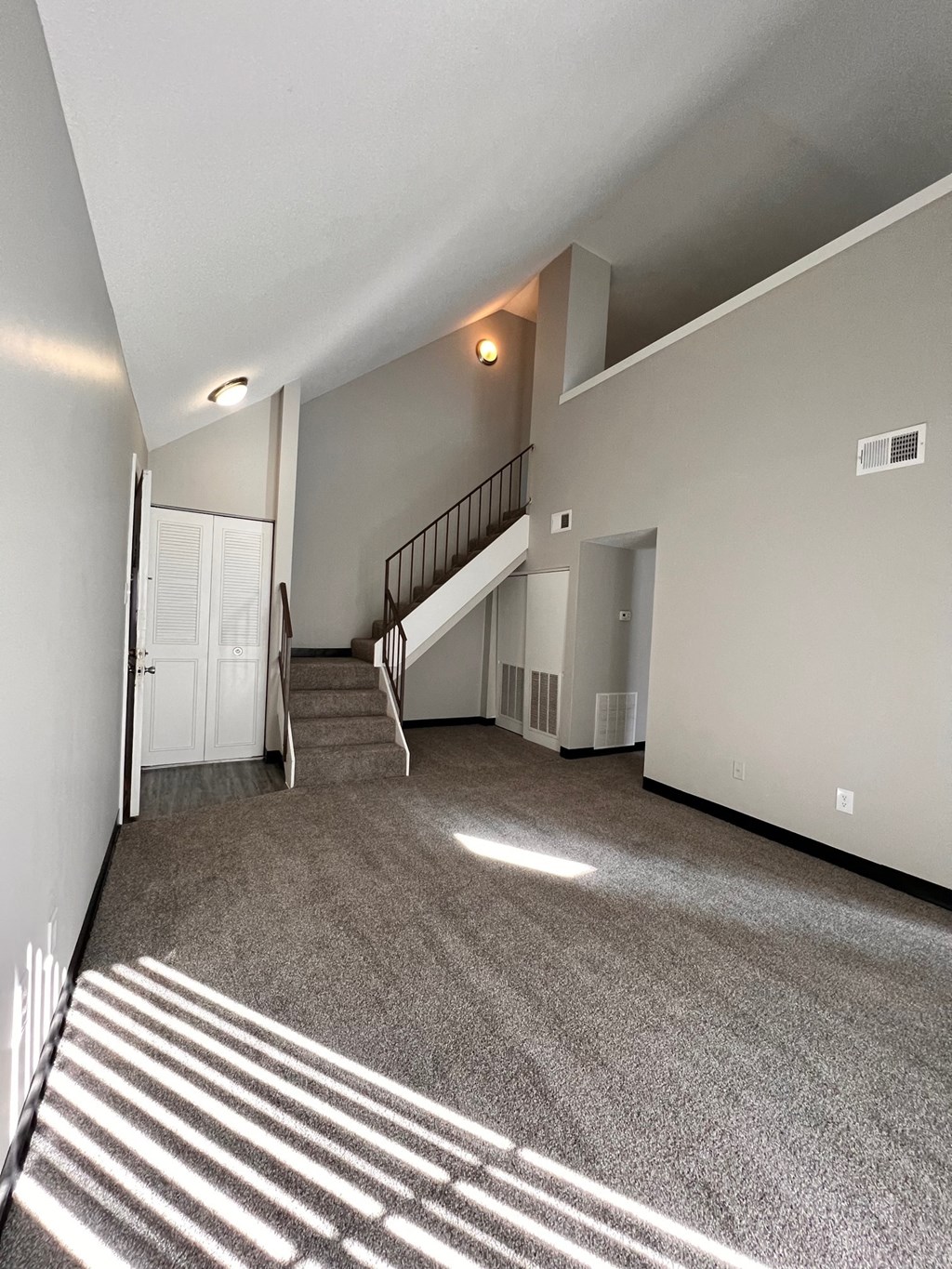 the upstairs living room of an empty house with carpeted stairs