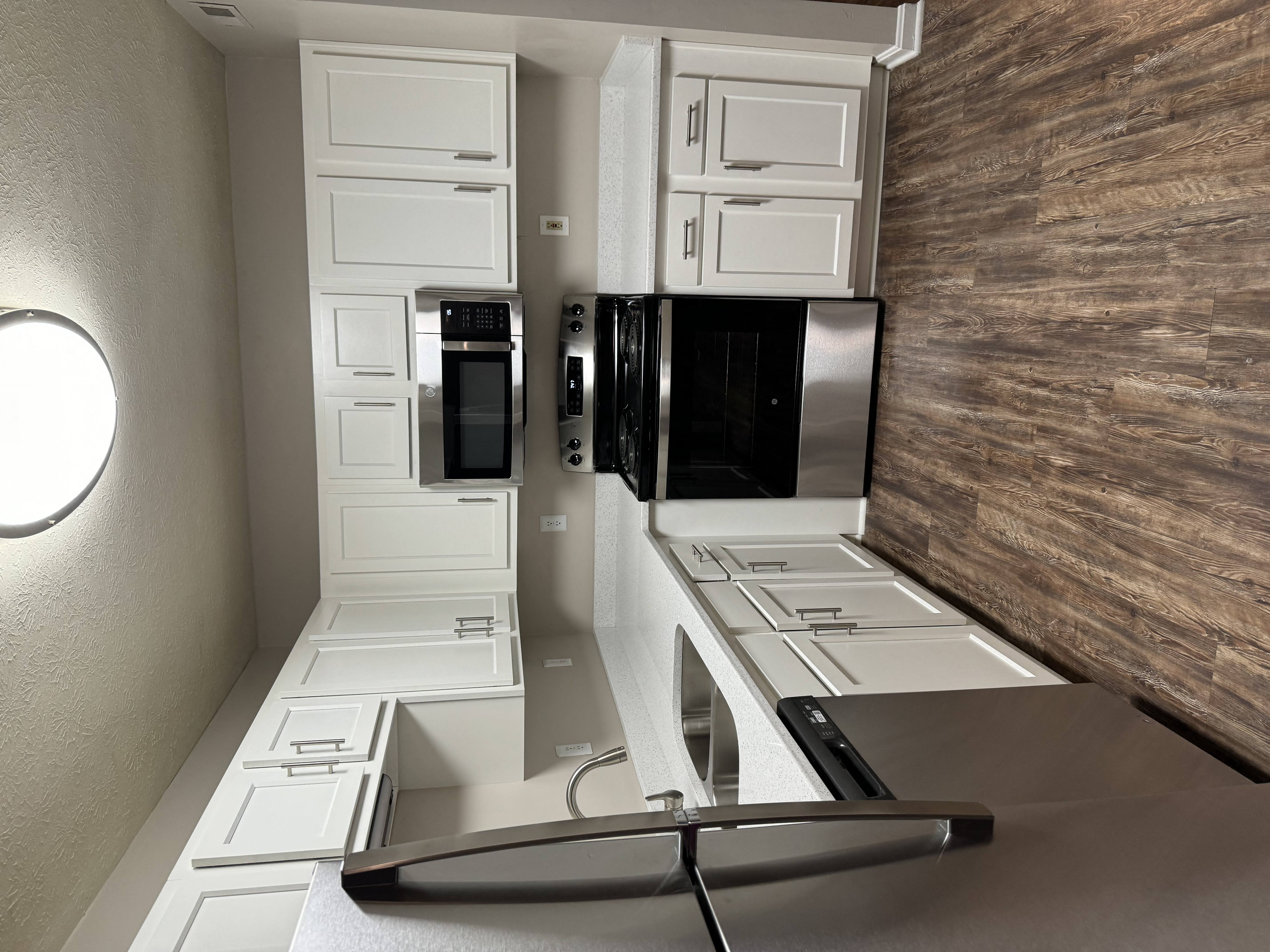 A modern kitchen with white cabinets and stainless steel appliances.