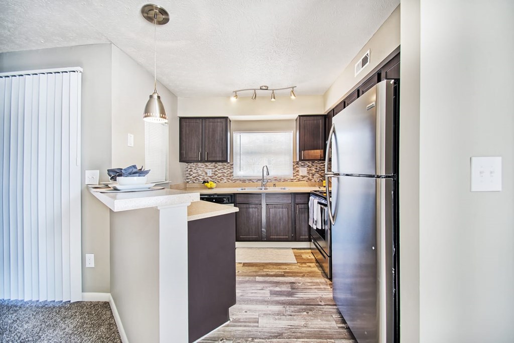 A kitchen with a refrigerator, sink, and cabinets.