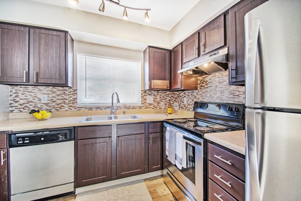 A kitchen with dark wood cabinets and stainless steel appliances.