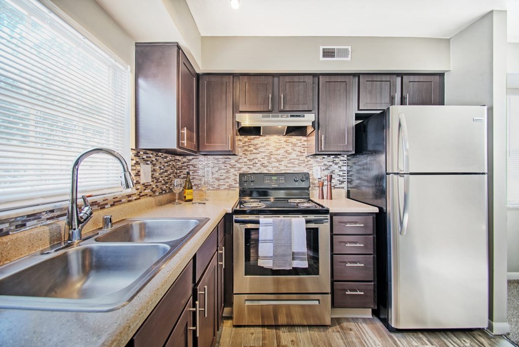 A modern kitchen with dark wood cabinets and stainless steel appliances.