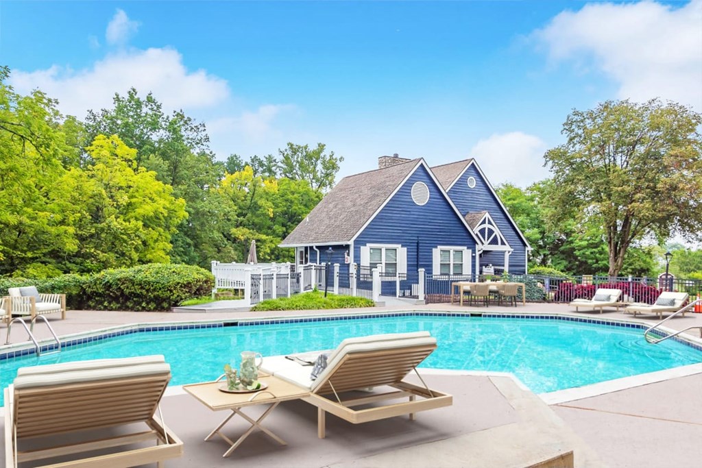 A poolside table with chairs and a house in the background.