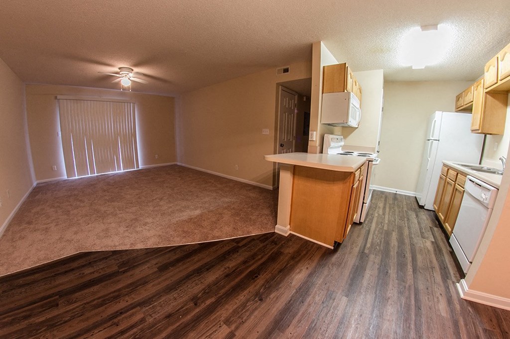 an empty kitchen and living room with wood floors