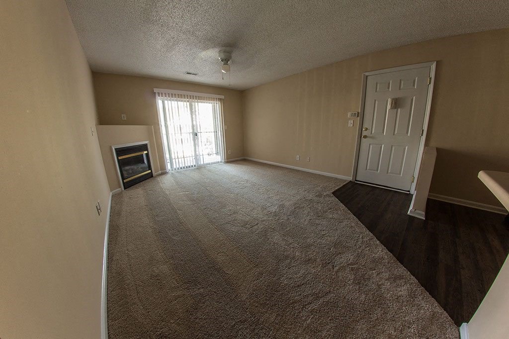 an empty living room with a fireplace and a white door