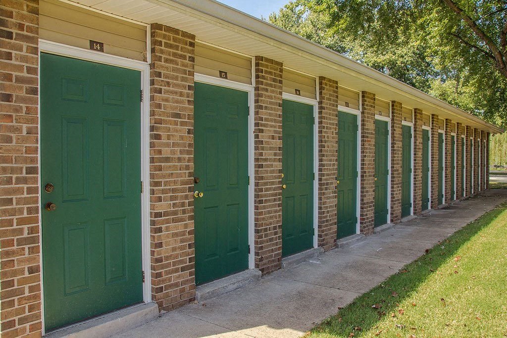 a row of green doors on a brick building