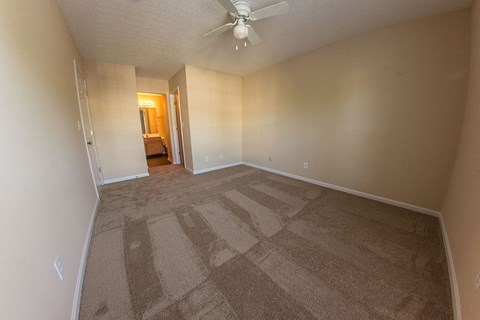 a empty living room with carpet and a ceiling fan