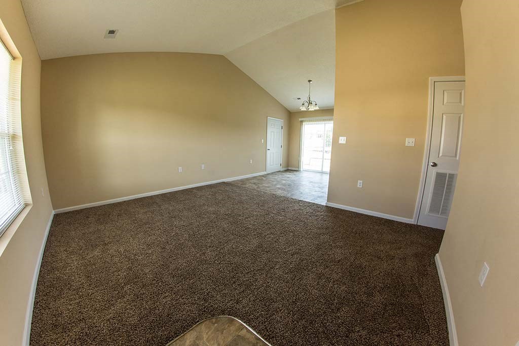 an empty living room with carpet and a door
