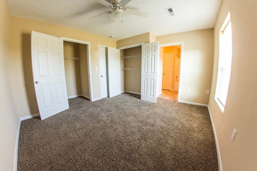 an empty living room with empty closets and a ceiling fan