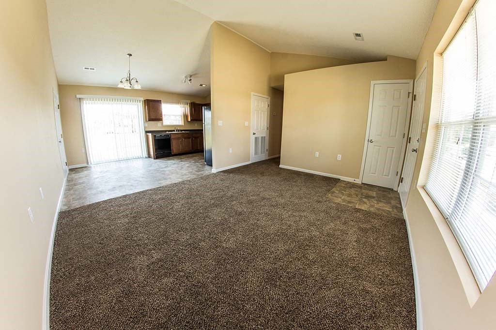 an empty living room and kitchen with a carpet