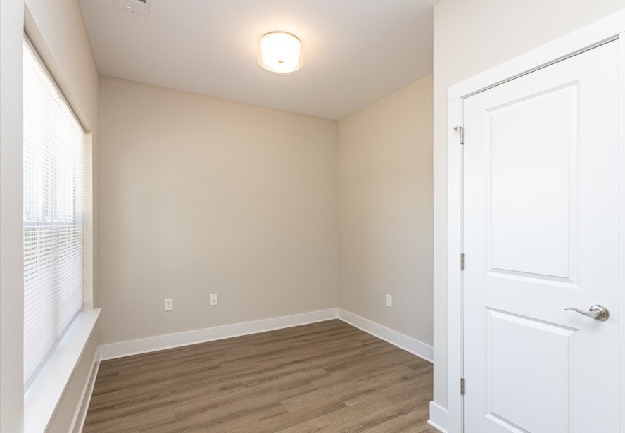 A room with a white door and a window with blinds.