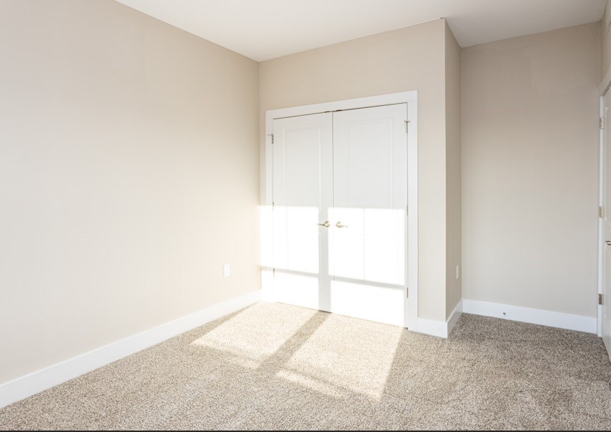 A room with a white door and carpeted floor.