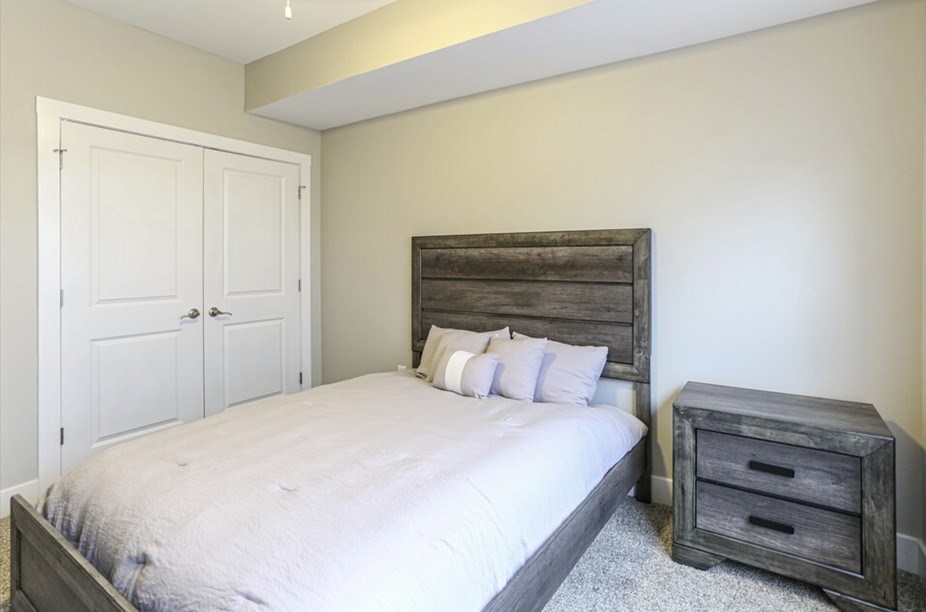 A bedroom with a bed, nightstand, and wardrobe.