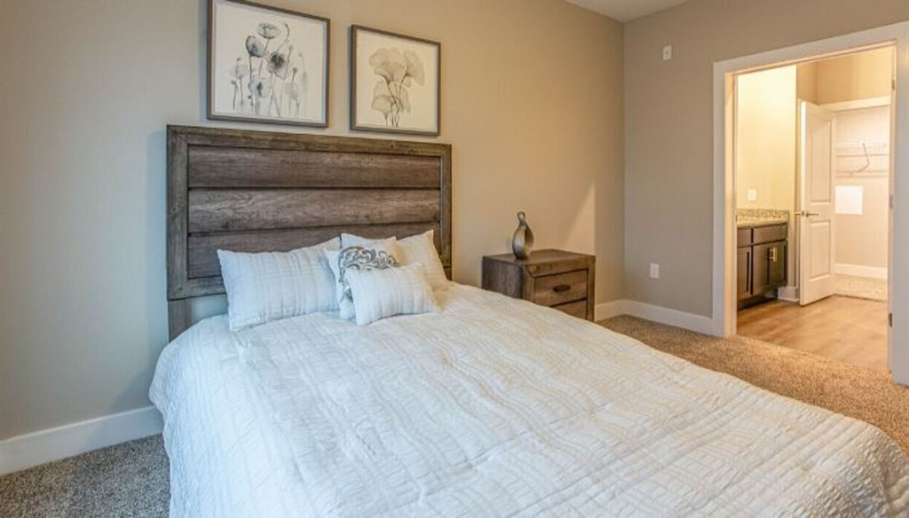 A bedroom with a large bed and two pictures on the wall.