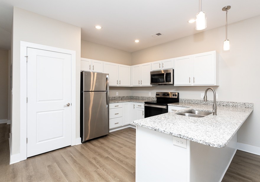 A kitchen with white cabinets and a granite countertop.