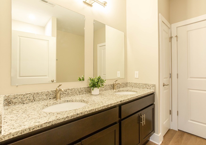 A bathroom with a double sink and a mirror above it.