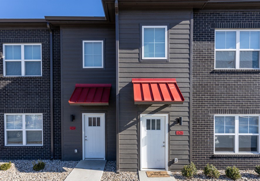 A building with a red awning and two white doors.