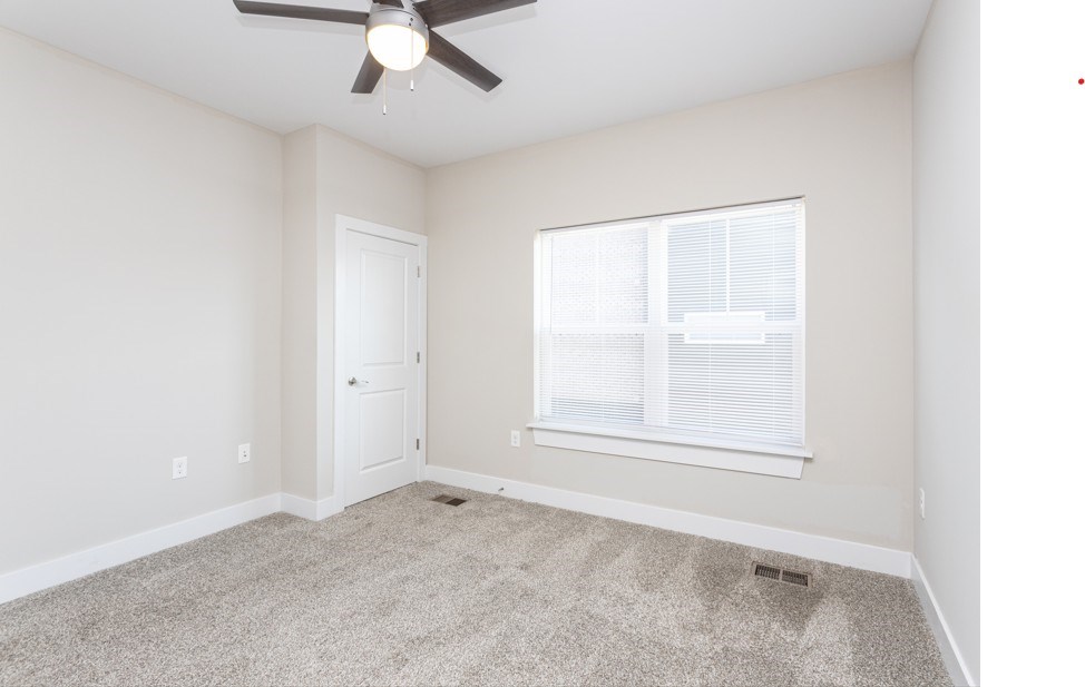 A room with a ceiling fan and a window with blinds.