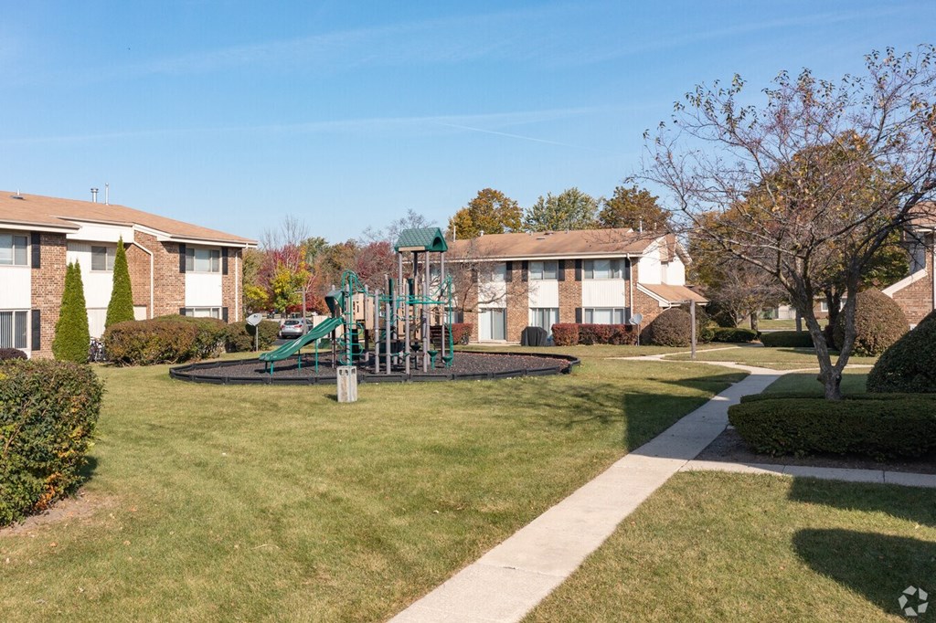 a playground in the middle of a yard in front of some apartments