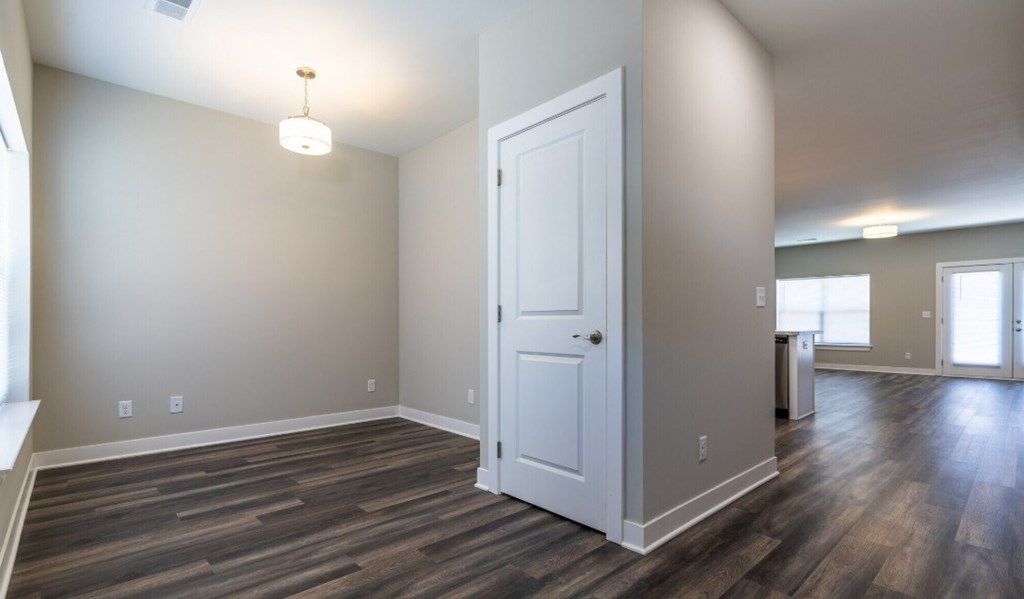 A room with a white door and wooden flooring.