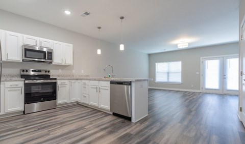 A kitchen with white cabinets and a wooden floor.