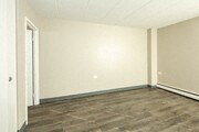an empty room with white walls and wood floors