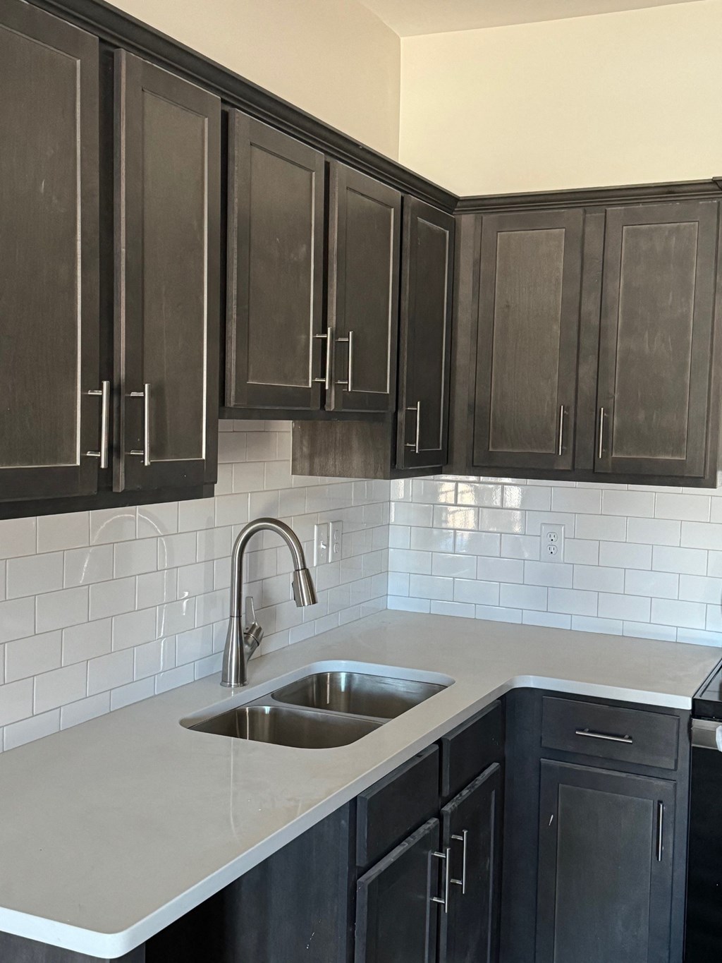 a kitchen with black cabinets and white tile and a sink