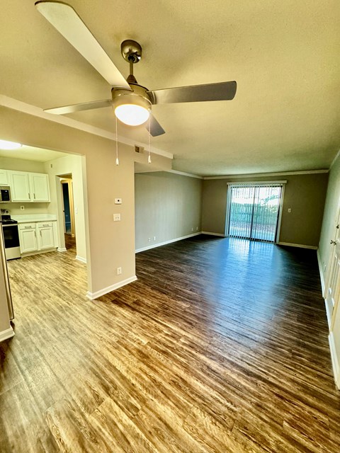 A room with a ceiling fan and wooden flooring.