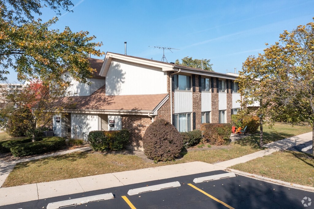a white and brick apartment building with grass and trees