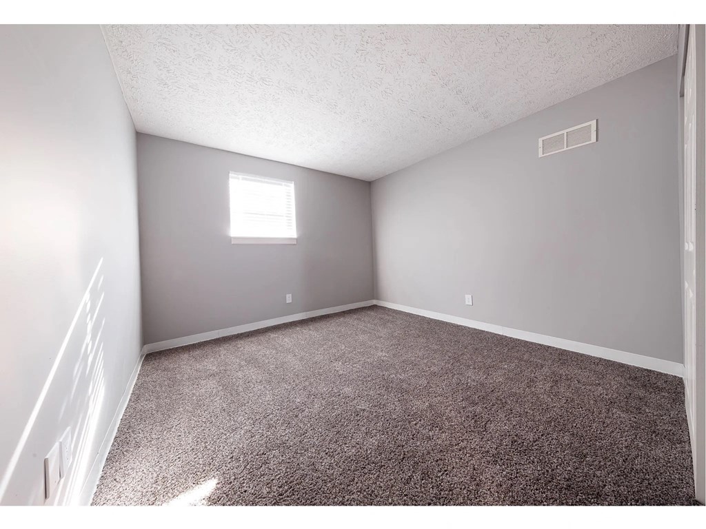 an empty room with carpet and a window