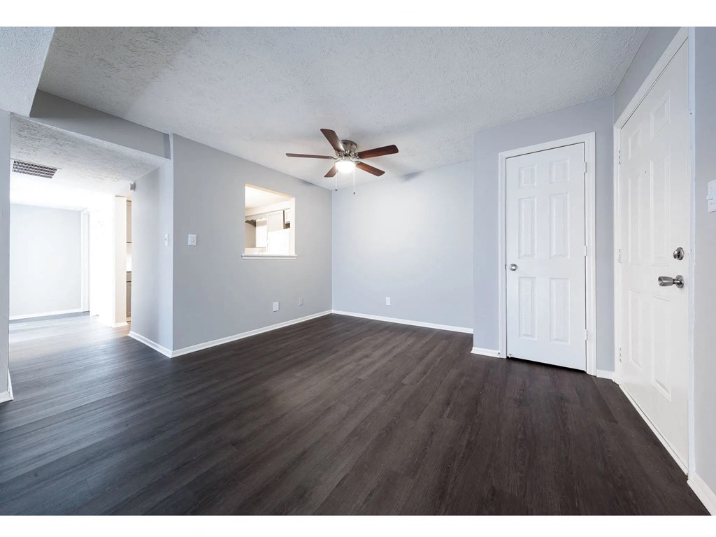 an empty living room with white walls and a ceiling fan