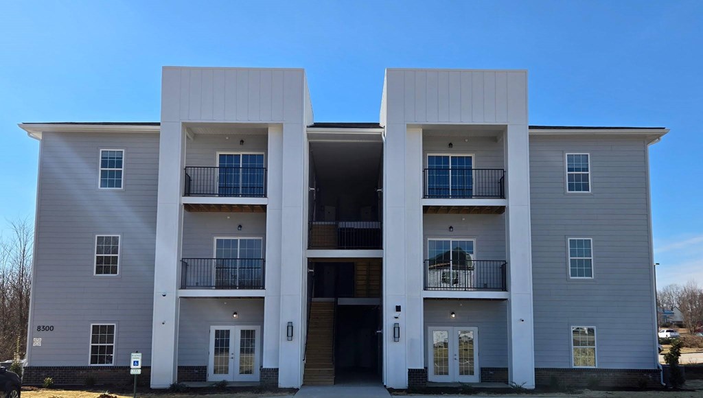 A modern two-story apartment building with balconies on the second floor.