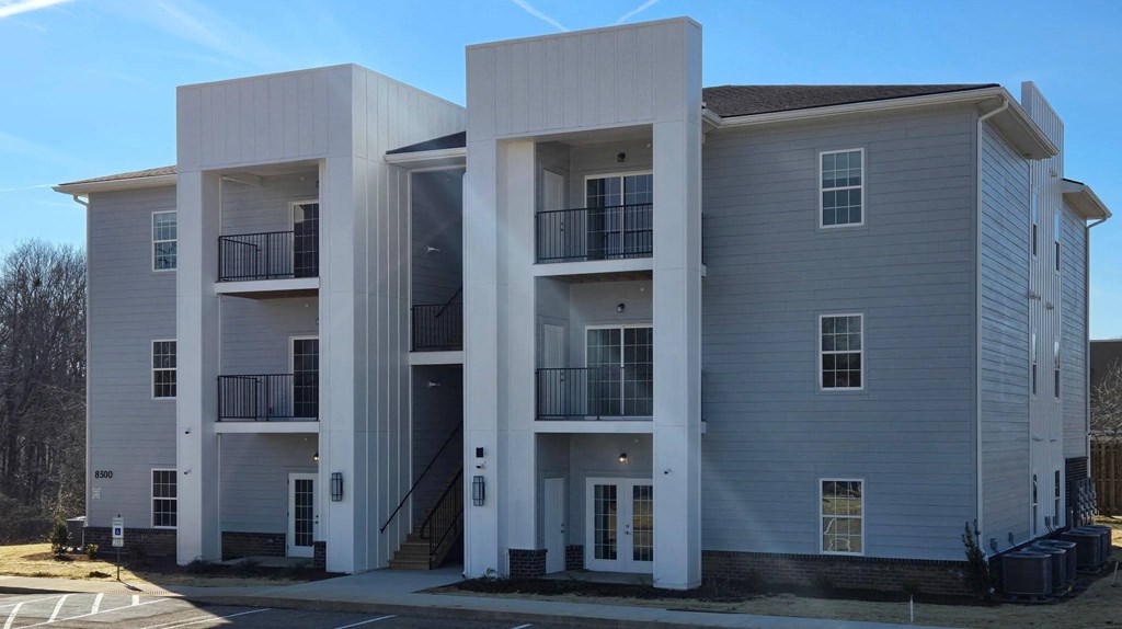 A modern apartment building with a parking lot in front.