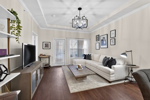A living room with a white couch and a wooden floor.