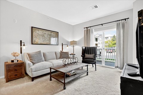 A living room with a grey couch, a coffee table, and a painting on the wall.