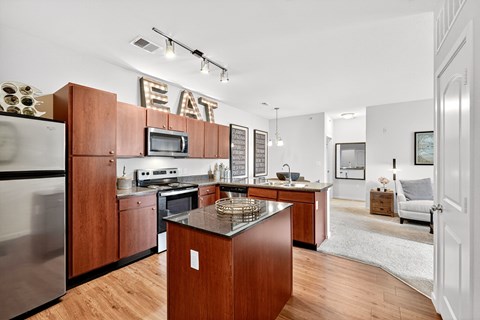 A modern kitchen with wooden cabinets and a stainless steel refrigerator.
